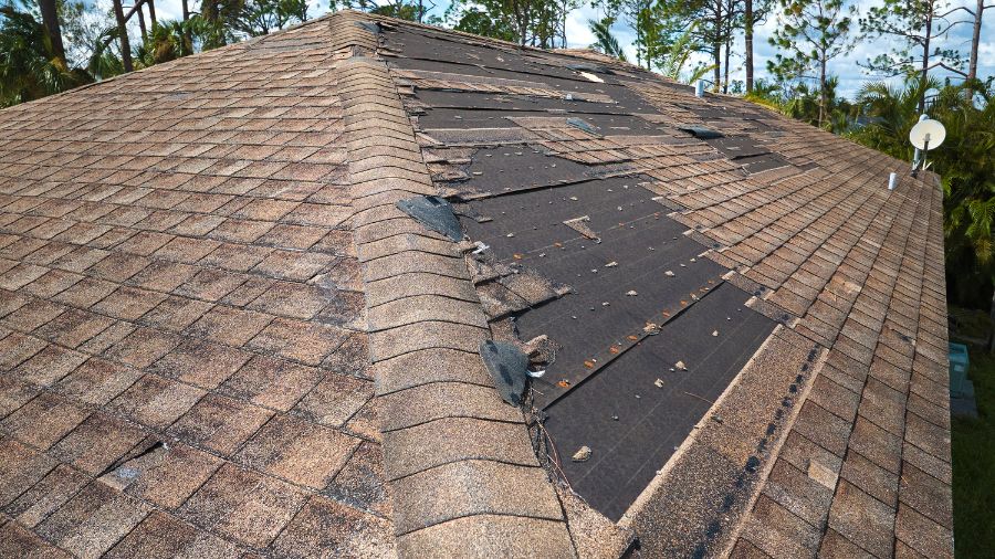 Licensed contractor inspecting storm-damaged roof for emergency repair.