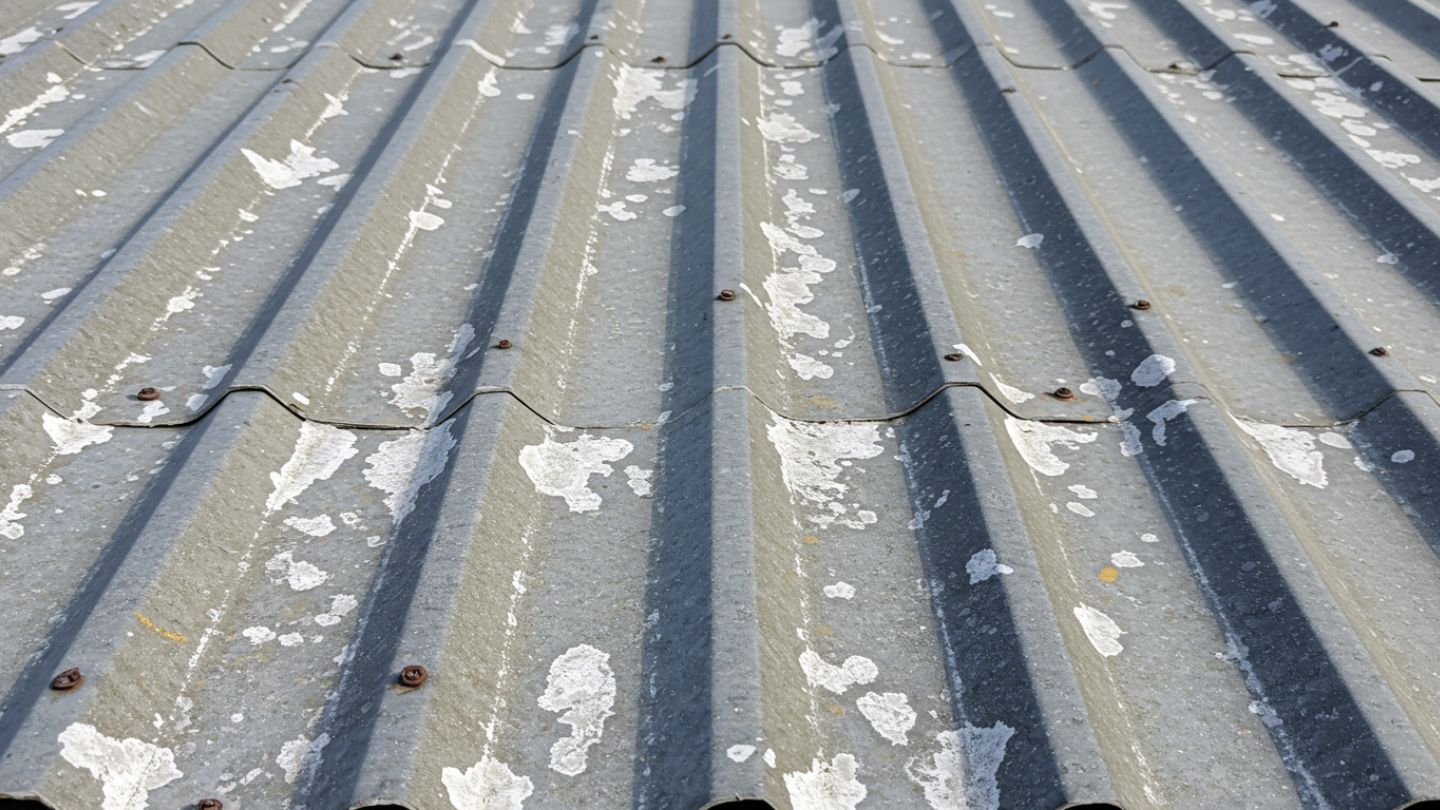 Split view of faded, chalky metal roof before restoration and vibrant roof after repainting